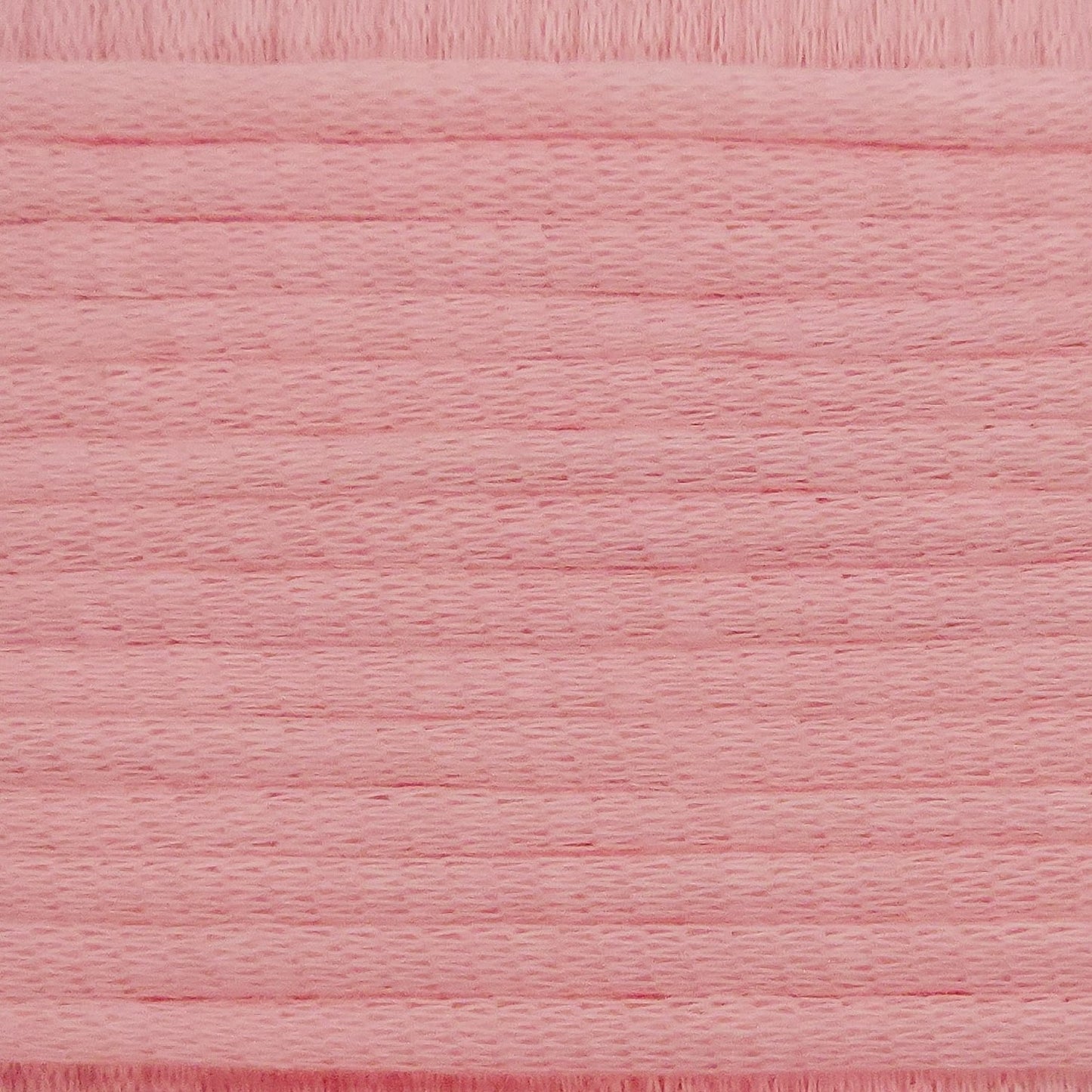 A close-up image showing the texture of a baby pink coloured yarn that is friendly for crochet beginners.