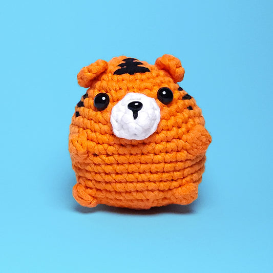 Cute chubby orange tiger amigurumi with black stripes, made from our beginner-friendly crochet kit. Perfect for those new to crocheting, showcasing its adorable and detailed design. Front view.