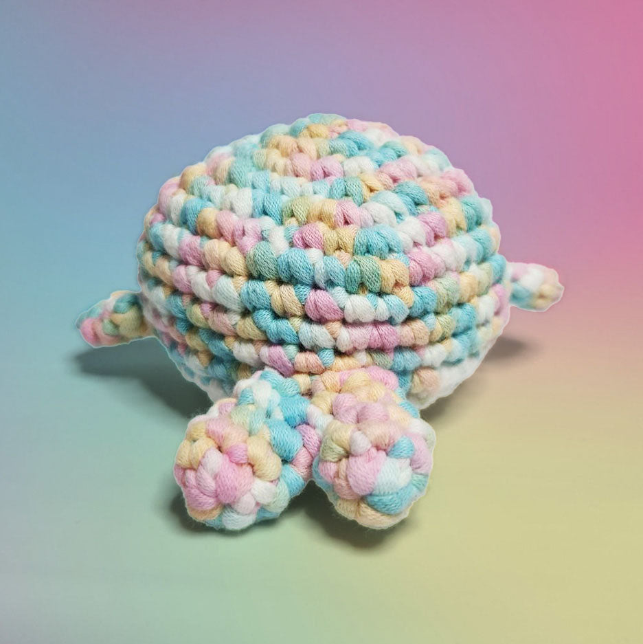 Pastel rainbow and white amigurumi whale, handcrafted with care. Made from our beginner-friendly crochet kit, perfect for those new to crocheting. Back view.
