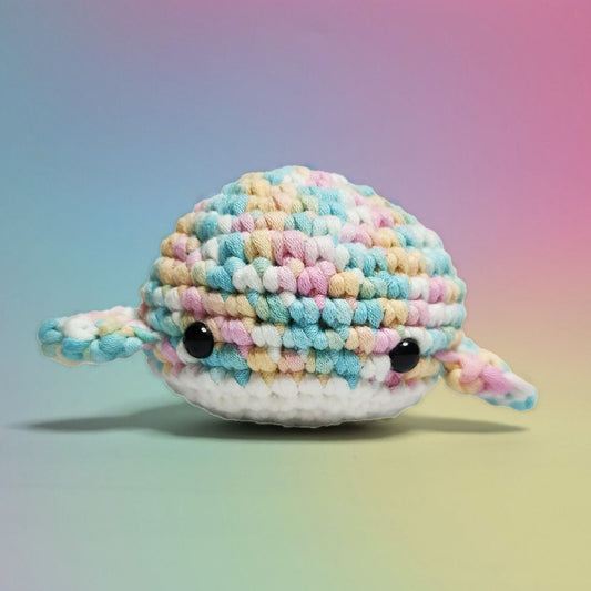 Pastel rainbow and white amigurumi whale, handcrafted with care. Made from our beginner-friendly crochet kit, perfect for those new to crocheting. Front view.