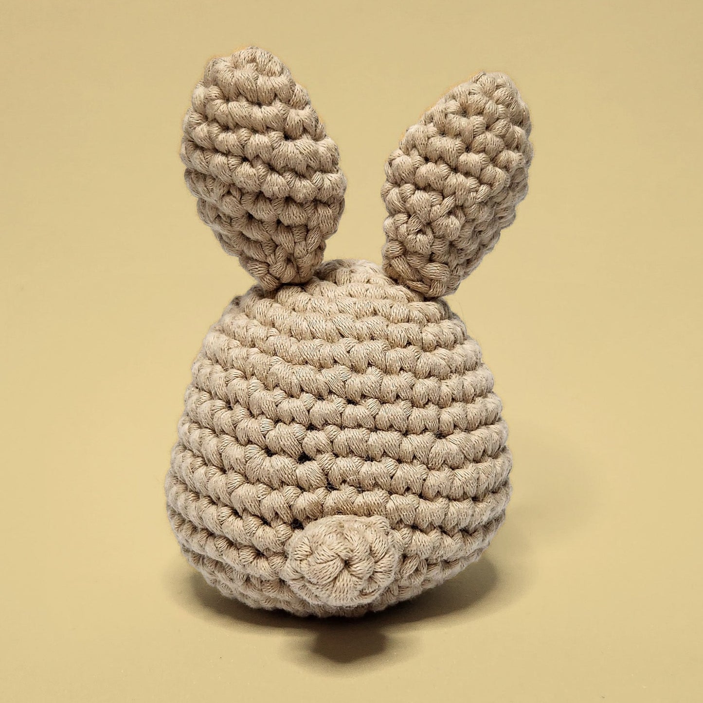 Brown bunny crochet amigurumi, a completed project from our beginner-friendly crochet kit. Handmade with our yarn, perfect for people who are looking to learn crocheting. Back view.