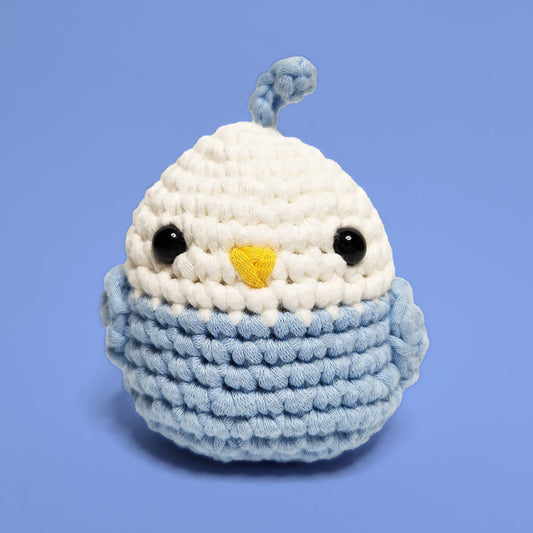 Blue and white lovebird crochet amigurumi with a cute feather accent. Handcrafted from our beginner-friendly crochet kit, ideal for those eager to learn crocheting. Front view.