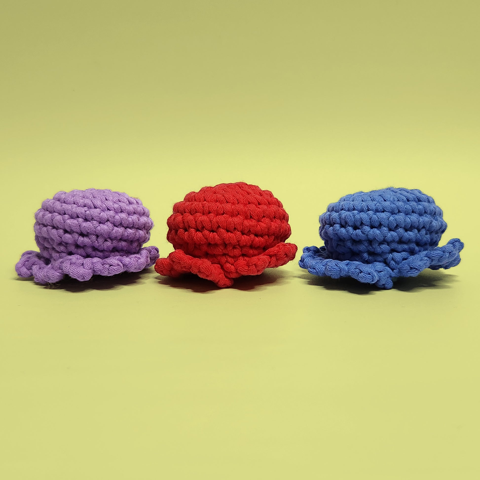 Red, blue, and purple octopus crochet amigurumi set. Handcrafted from our beginner-friendly crochet kit, perfect for those new to crocheting. Back view displaying vibrant colors.
