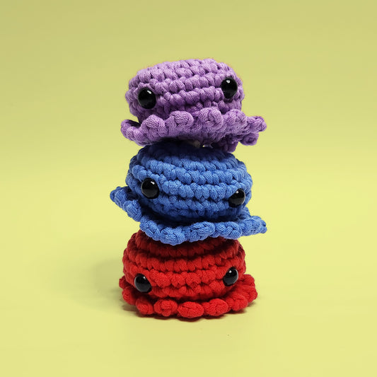 Red, blue, and purple octopus crochet amigurumi set. Handcrafted from our beginner-friendly crochet kit, perfect for those new to crocheting. Front view displaying vibrant colors.