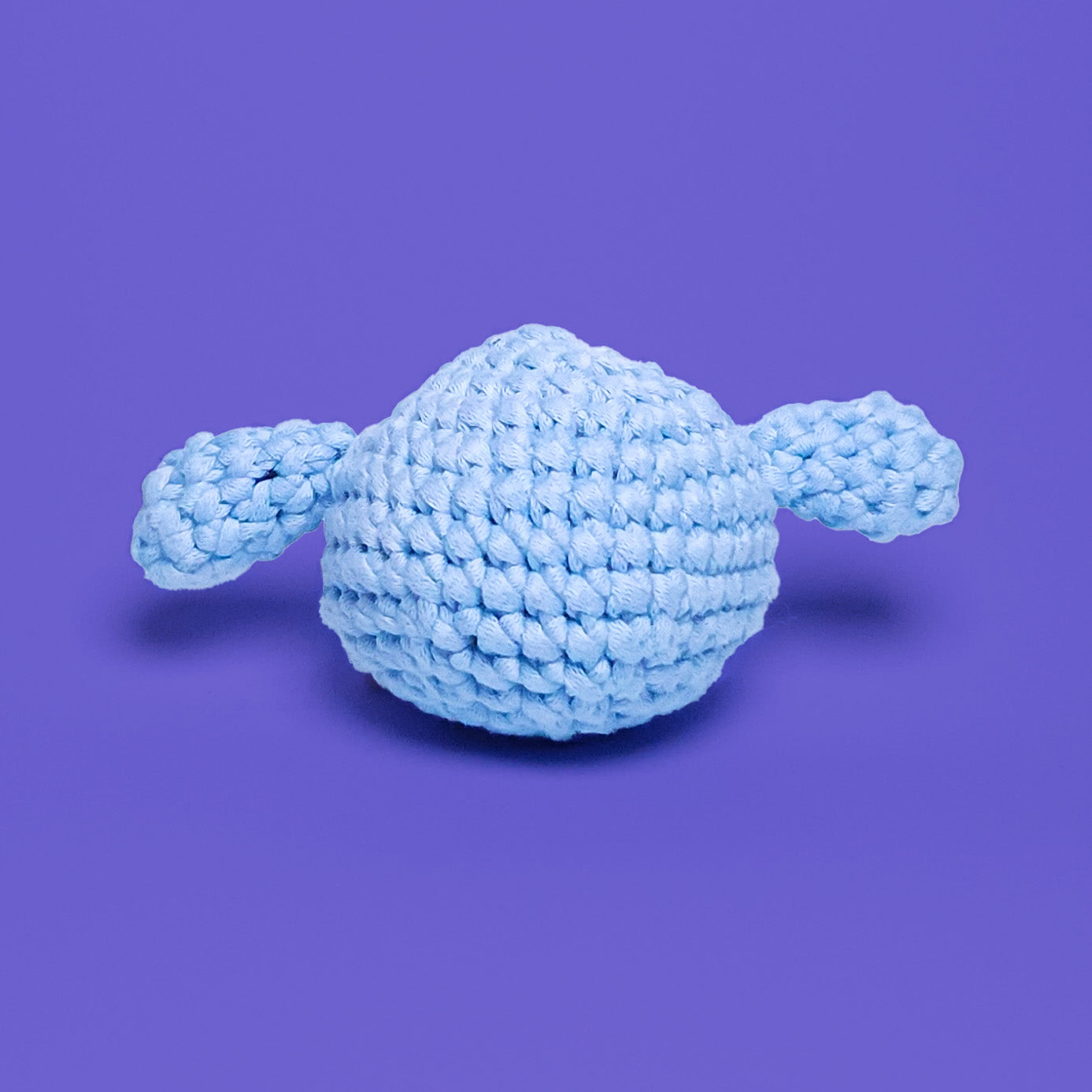 Blue crochet amigurumi elephant head, with long ears at the side. Made from our beginner-friendly crochet kit, ideal for beginners looking to learn crocheting. Back view.
