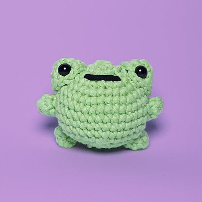 Cute green amigurumi frog, handcrafted from our beginner-friendly crochet kit. Ideal for beginners learning to crochet. Front view.
