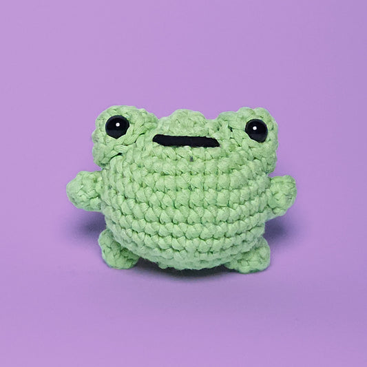 Cute green amigurumi frog, handcrafted from our beginner-friendly crochet kit. Ideal for beginners learning to crochet. Front view.