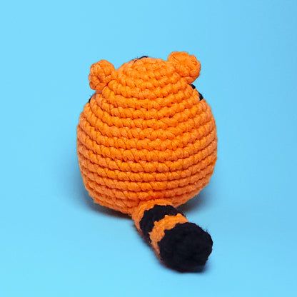 Cute chubby orange tiger amigurumi with black stripes, made from our beginner-friendly crochet kit. Perfect for those new to crocheting, showcasing its adorable and detailed design. Back view.