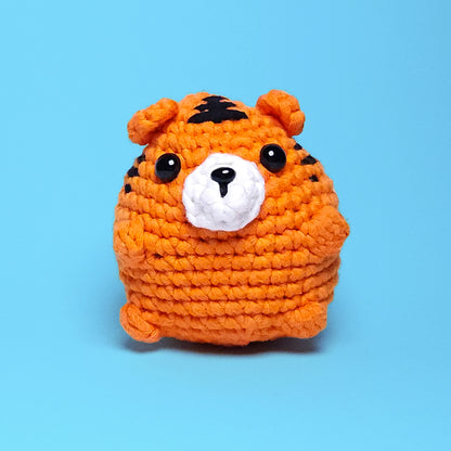 Cute chubby orange tiger amigurumi with black stripes, made from our beginner-friendly crochet kit. Perfect for those new to crocheting, showcasing its adorable and detailed design. Front view.