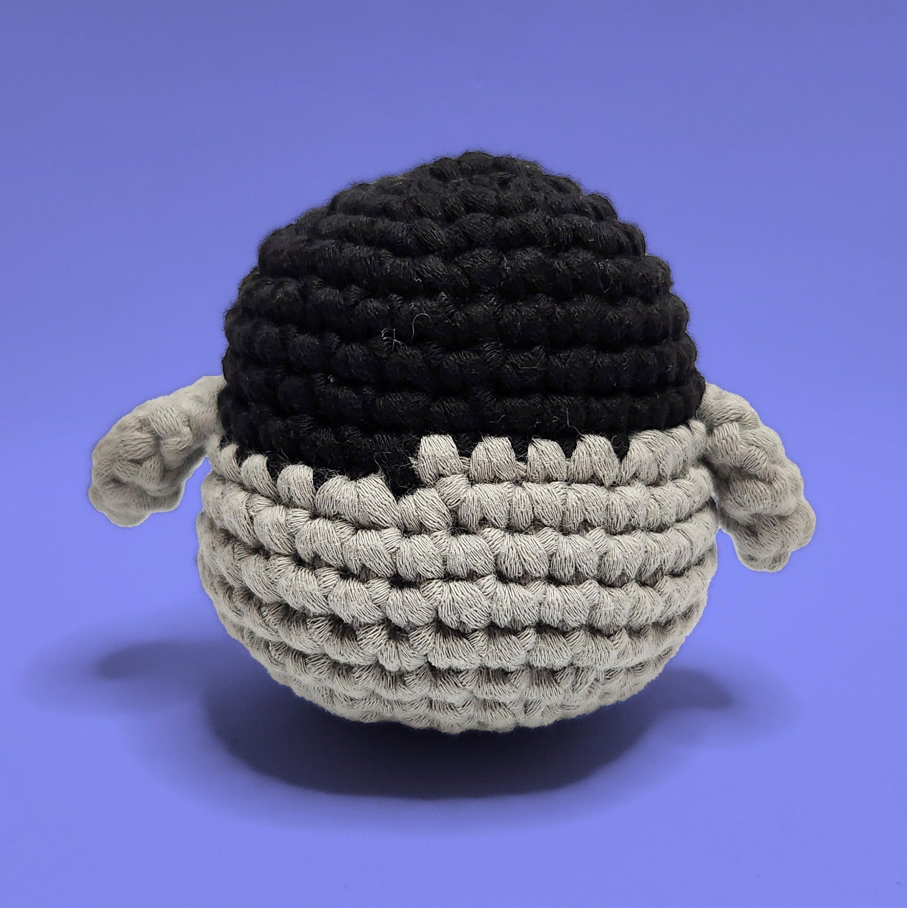 Lola the black, grey and white penguin crochet amigurumi, handmade with love. This adorable penguin with yellow legs is perfect for bringing joy and cheer. Back view, ideal for crochet enthusiasts and penguin lovers.