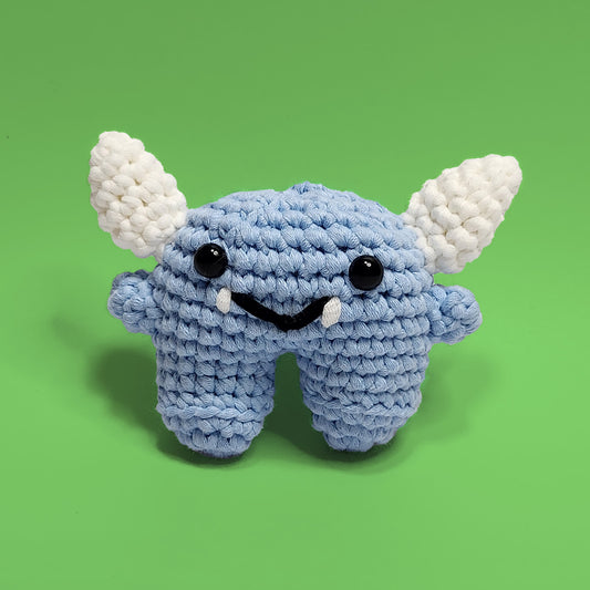 Nero, the fearsome aqua monster crochet amigurumi, featuring a striking blue color with fangs and horns. Handcrafted with attention to detail, Nero is a unique and adventurous project perfect for crafters looking for a challenge. Front view.