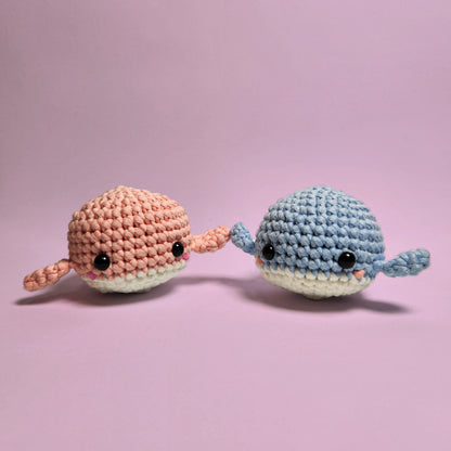 Pair of adorable amigurumi whales, one blue and one pink, with blush accents. Handcrafted with care and attention to detail, perfect for those new to crocheting. Front view.