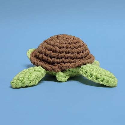 Green smiley turtle crochet amigurumi with a brown shell, made using our own beginner-friendly crochet kit. Handcrafted with love, this cheerful turtle is a delightful addition to any collection. Back view.