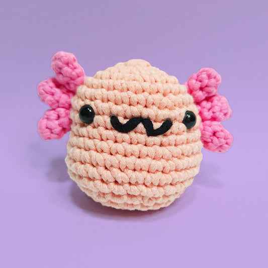 Pink axolotl crochet amigurumi, a charming creation perfect for axolotl enthusiasts. Handcrafted with care using our beginner friendly crochet kits. Front view.